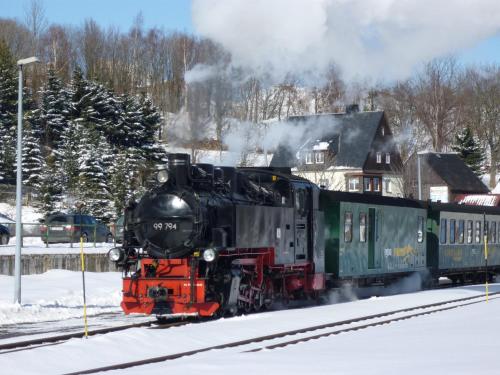 a train traveling down the tracks in the snow at Ferienwohnungen "Am Schlössel" in Kurort Oberwiesenthal