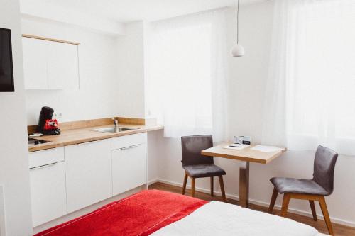 una cocina con 2 sillas y una mesa con fregadero en HEIMAT | Hotel & Boarding House, en Mainburg
