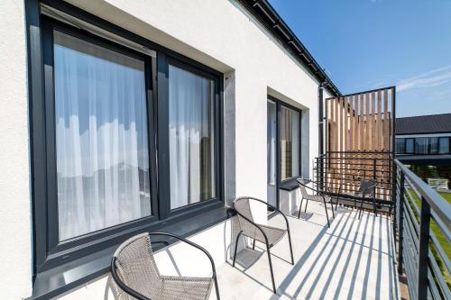 a balcony with chairs and windows on a building at Siesta in Grzybowo