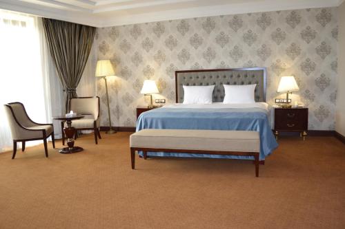 a bedroom with a bed and two chairs and two lamps at Sultan Plaza hotel in Qyzylorda