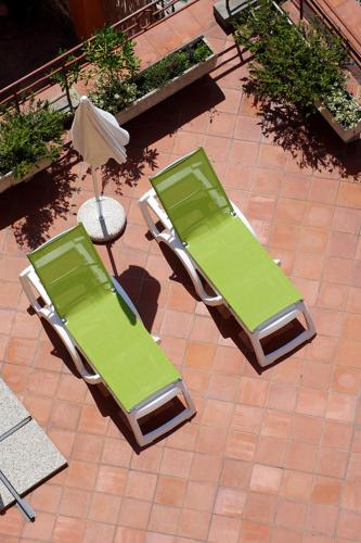 two green chairs and an umbrella on a patio at Hotel Kristina in Imperia