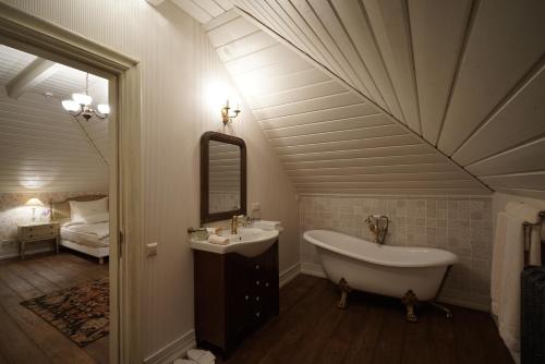 a bathroom with a tub and a sink and a mirror at Liepupe Manor in Liepupe