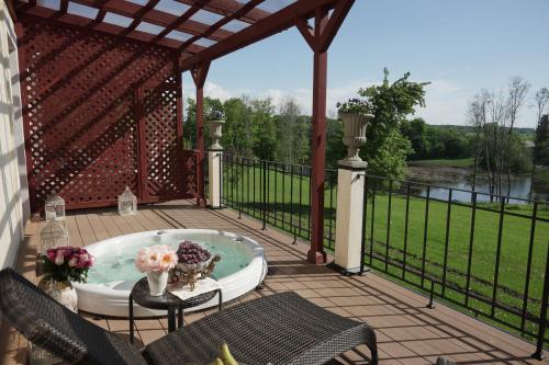 a patio with a hot tub and a fence at Liepupe Manor in Liepupe
