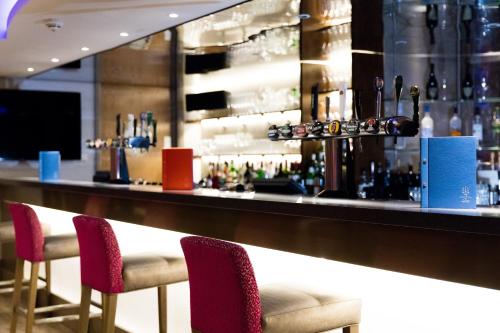 a bar with red chairs in front of a counter at The Royal Yacht in Saint Helier Jersey