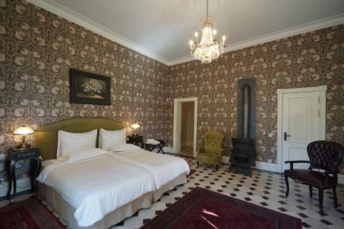 a bedroom with a large bed and a chandelier at Liepupe Manor in Liepupe