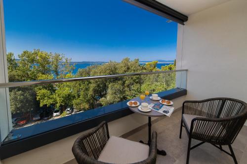 a balcony with a table and chairs and a large window at Boutique Hotel Esplanade - Adults only in Crikvenica