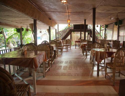 an empty restaurant with tables and chairs and a staircase at Symphony Palms Beach Resort And Spa in Havelock Island