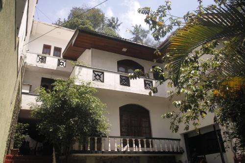 a white house with a balcony and trees at Kandy Citylights Residence in Kandy