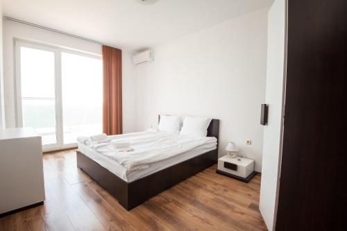 a white bedroom with a bed and a large window at Momchil Villas in Balchik