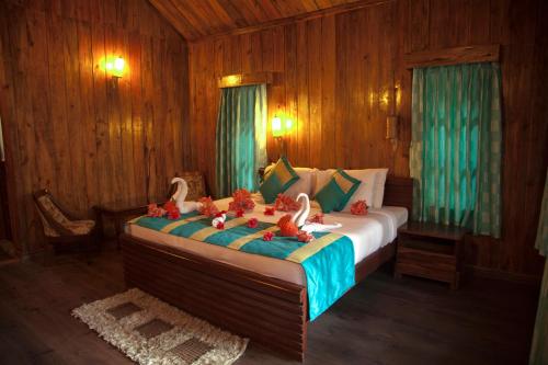 a bedroom with a bed, a dresser, and a lamp at Symphony Palms Beach Resort And Spa in Havelock Island