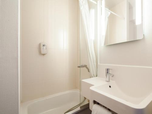 a white bathroom with a sink and a shower at B&B HOTEL Creil Chantilly in Creil