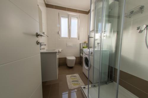 a bathroom with a washing machine and a glass shower at Apartments Bouvier in Pag