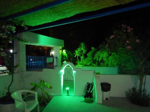 a house lit up at night with a green light at Iris Studios in Archangelos