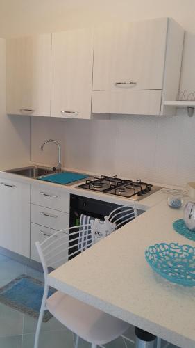 a white kitchen with a stove and a table at Acquamarina Accommodation in Massa Lubrense