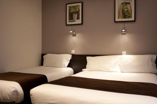 two beds in a hotel room with two at Hotel Cosmos in Paris