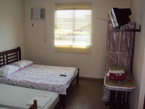 a room with two beds and a television in it at Skandalo Pub Pousada in Rio das Ostras