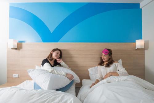 two women sitting on beds in a hotel room at Hop Inn Hotel Makati Avenue Manila in Manila
