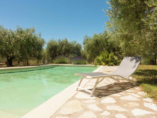 een witte stoel naast een zwembad bij Beautiful holiday home with pool in Autignac