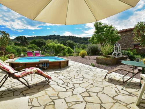 eine Terrasse mit einem Sonnenschirm und einem Pool in der Unterkunft Holiday home with swimming pool in Félines-Minervois