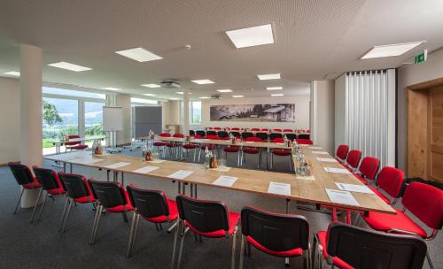 a conference room with a long table and red chairs at Panorama Hotel Gasthof Leidingerhof in Mondsee