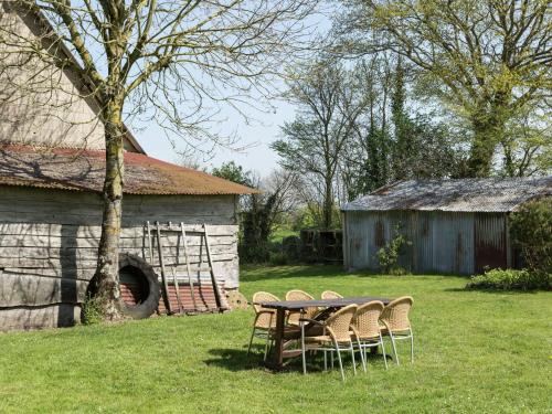 einen Tisch und Stühle auf einem Feld neben einer Scheune in der Unterkunft Rustic holiday home with garden in Normandy in Gouvets