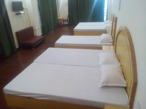 three beds in a room with green curtains at Trimurti Pine Valley Resort in Shimla