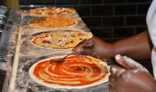 a person is making pizzas on a counter at Val Du Charron Wine & Leisure Estate in Wellington