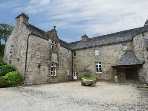 un antiguo edificio de piedra con un banco delante de él en Authentic manor house with terrace and pond en Plougonven