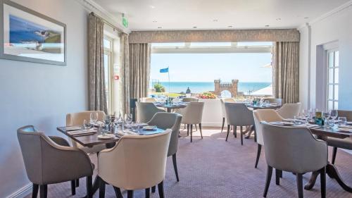 a dining room with tables and chairs and a large window at The Belmont Hotel in Sidmouth