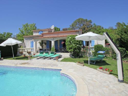 a house with a swimming pool with chairs and umbrellas at Beautiful holiday home with private pool in Bagnols-en-Forêt
