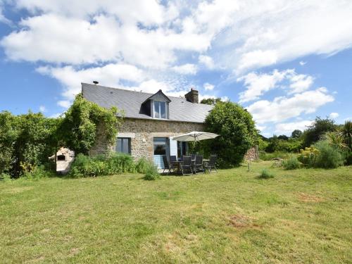 a stone house with chairs and an umbrella on a field at Lovely mansion with fenced garden in Baguer-Morvan