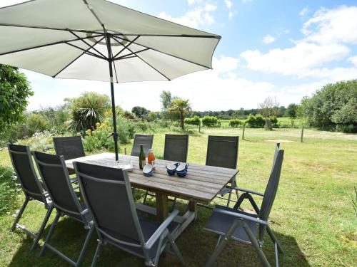einen Holztisch und Stühle mit Sonnenschirm in der Unterkunft Lovely mansion with fenced garden in Baguer-Morvan