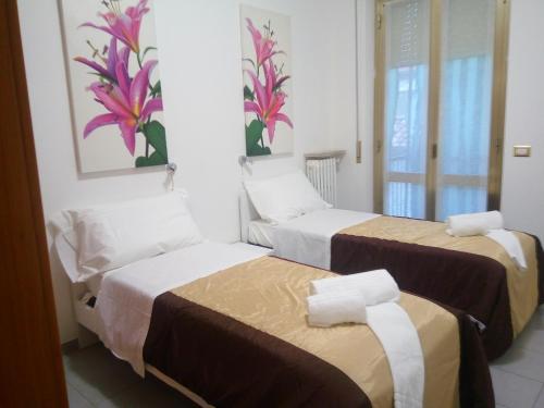 ヴェローナにあるAppartamento Le Campaneの花が飾られた壁の客室内のベッド2台