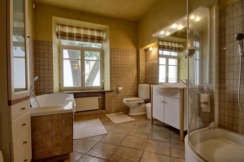 a bathroom with a tub and a sink and a toilet at Pilies Apartments in Vilnius