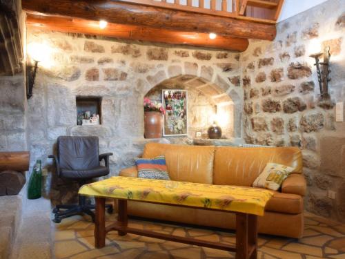 ein Wohnzimmer mit einem Sofa und einer Steinmauer in der Unterkunft Cosy holiday home on the river Le Lignon in La Souche