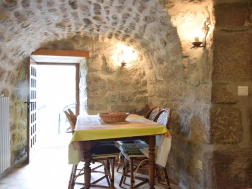 une table dans une pièce avec un mur en pierre dans l'établissement Cosy holiday home on the river Le Lignon, à La Souche