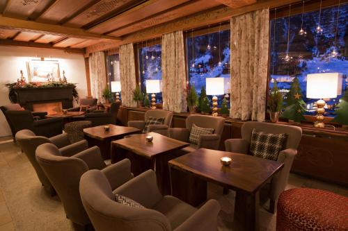 a restaurant with tables and chairs and a piano at Hotel Angela in Lech am Arlberg