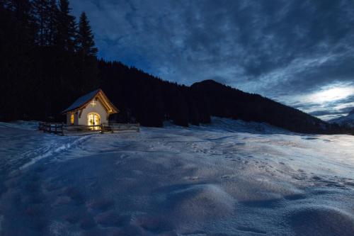 a small cabin with a light on in the snow at Hotel Angela in Lech am Arlberg