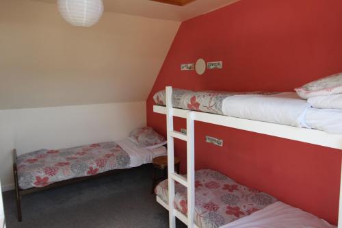 two bunk beds in a room with red walls at Skye Backpackers in Kyleakin
