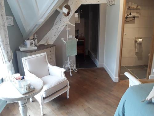 a room with a chair and a table and a staircase at Au Moulin de Valérie in Frencq
