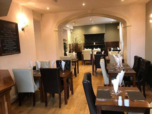 a restaurant with wooden tables and chairs and a chalkboard at Aberdunant Hall in Porthmadog