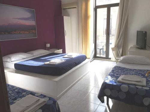 a hotel room with two beds and a balcony at Casa vacanza Civita Catania Centro in Catania