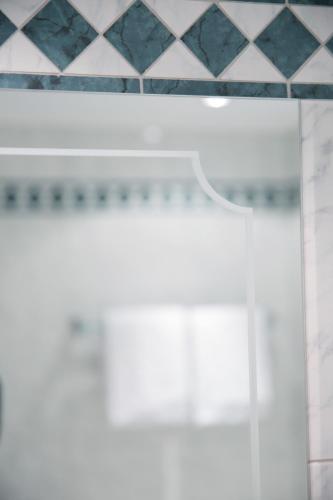 a glass door in a bathroom with a tiled wall at Hotel Angela in Lech am Arlberg