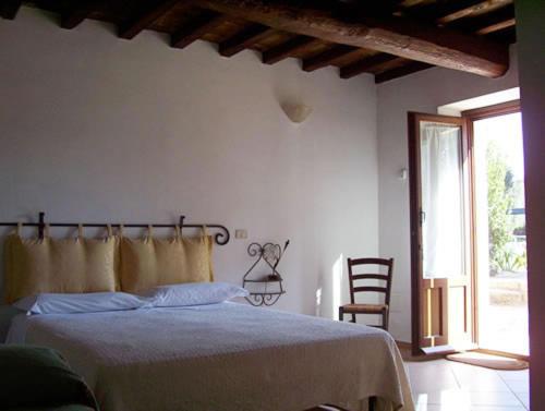 a bedroom with a bed and a chair and a window at Agriturismo Il Poggiolo in Montemerano