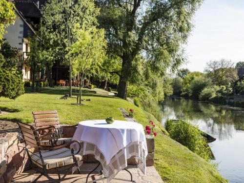 a table and chairs sitting next to a river at Hotel des Berges, Restaurant Gastronomique & Spa in Illhaeusern