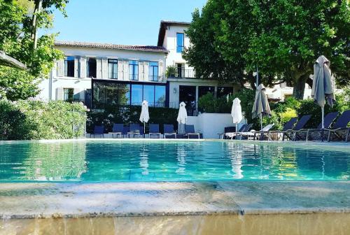 a swimming pool with chairs and umbrellas in front of a house at Les Lodges Sainte-Victoire Hotel & Spa in Aix-en-Provence