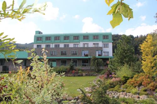 a building with a green roof in a garden at Hotel Bartoš in Frenštát pod Radhoštěm
