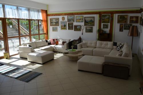 a living room with white couches and tables and windows at EldoSport Hotel in Dospat