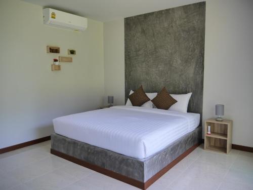 a bedroom with a large white bed and a night stand at Marisa Garden Bungalow in Bang Tao Beach