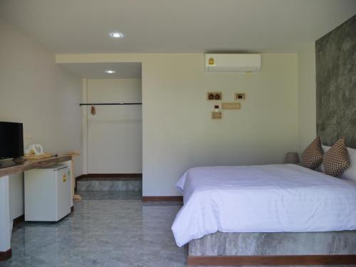 a bedroom with a white bed and a television at Marisa Garden Bungalow in Bang Tao Beach